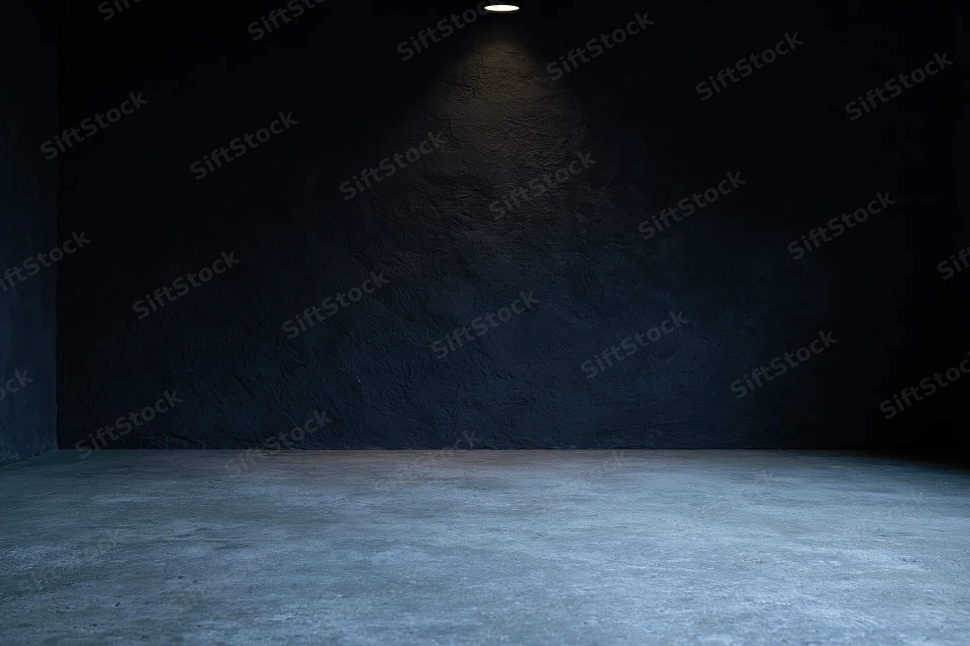 Empty dark studio interior with rough concrete floor and wall under spotlight