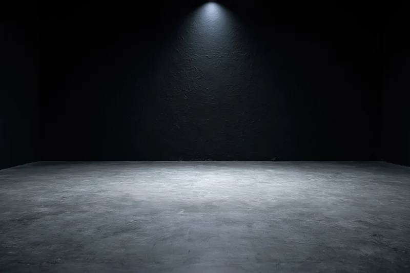 Spotlight on bare concrete floor in dark studio interior