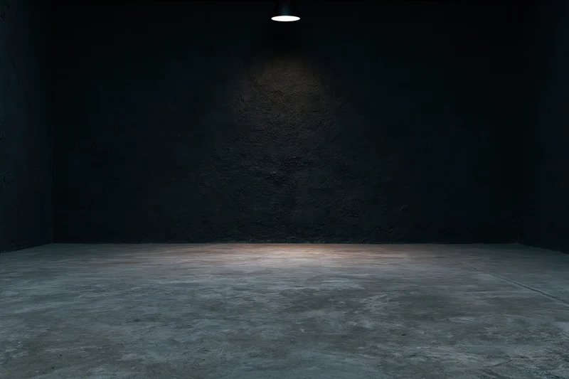 Empty dark studio interior with concrete floor and spotlight on rough wall