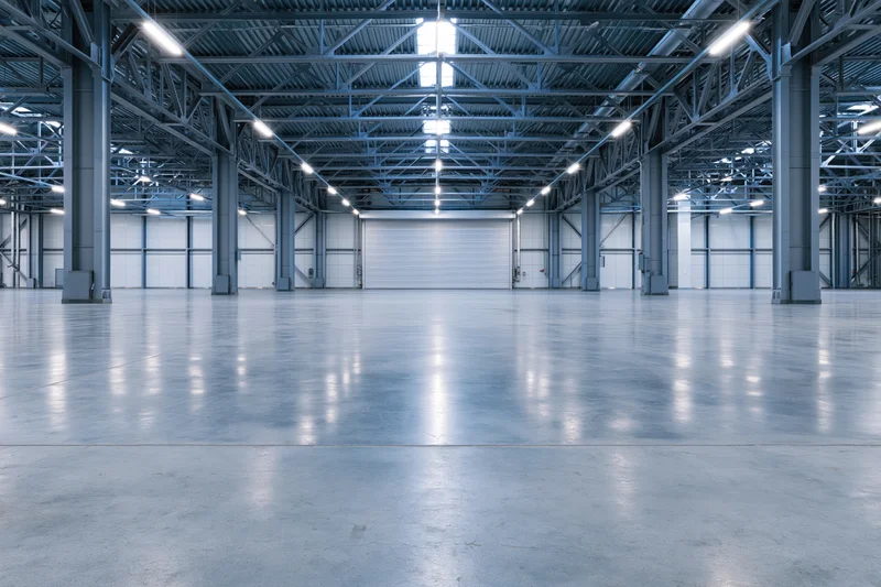 Empty industrial warehouse interior with symmetrical steel framework and polished concrete floor