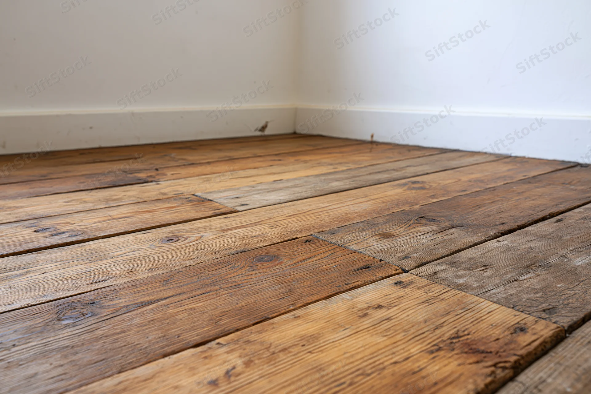 Worn wooden plank floor in empty interior corner