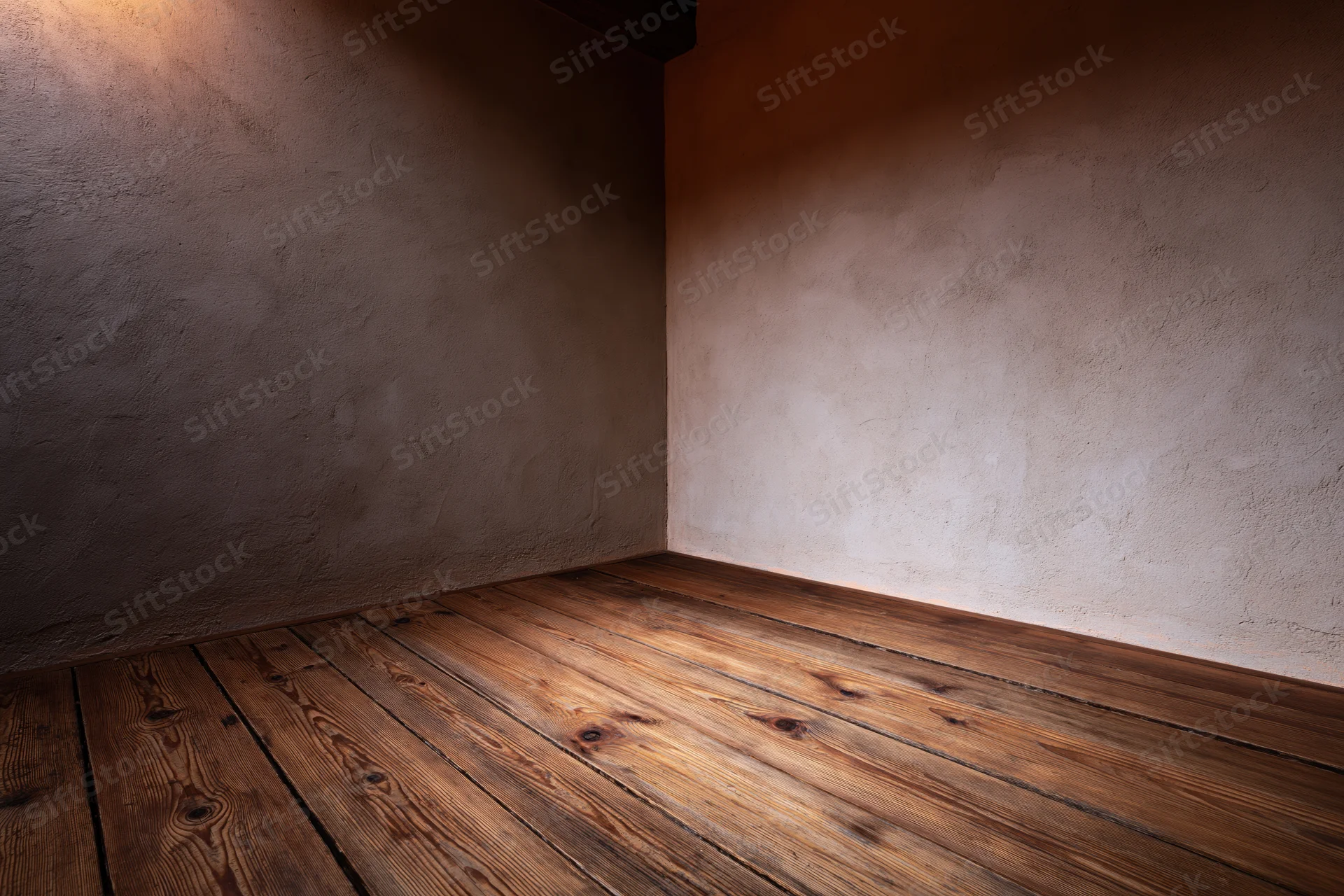 Empty room corner with wooden plank floor and plaster walls viewed from low angle