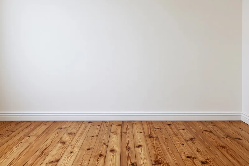 Empty interior room with plain white wall and bare wooden floor