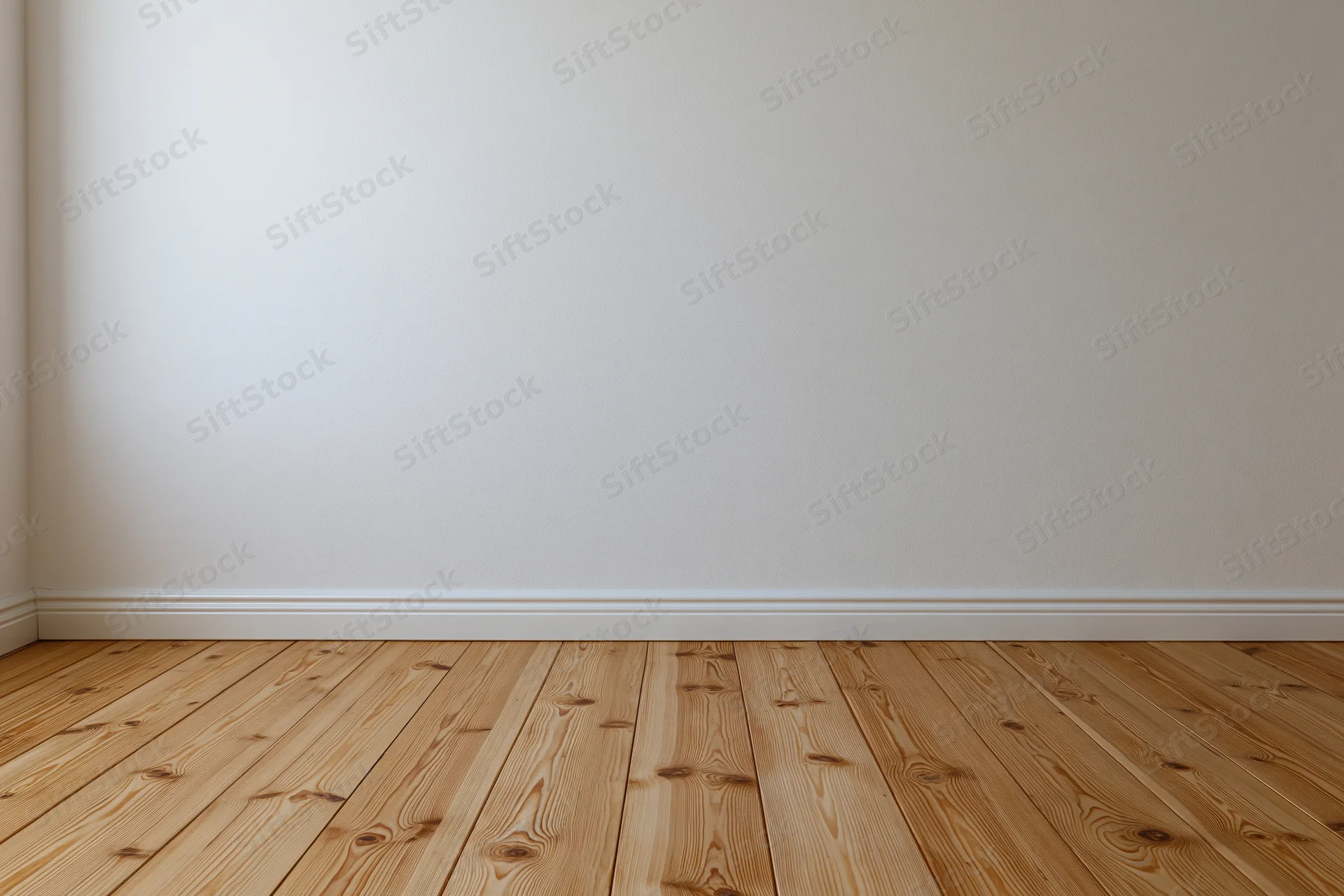 Empty interior room with plain white wall and bare wooden floor