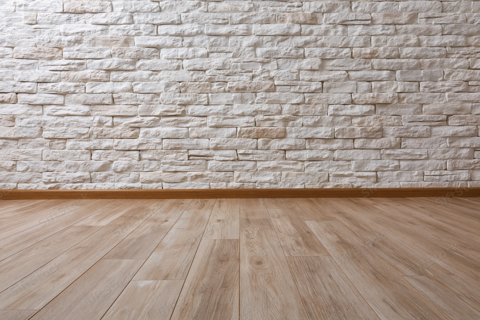 Empty interior room with whitewashed stacked stone brick wall and light wood flooring