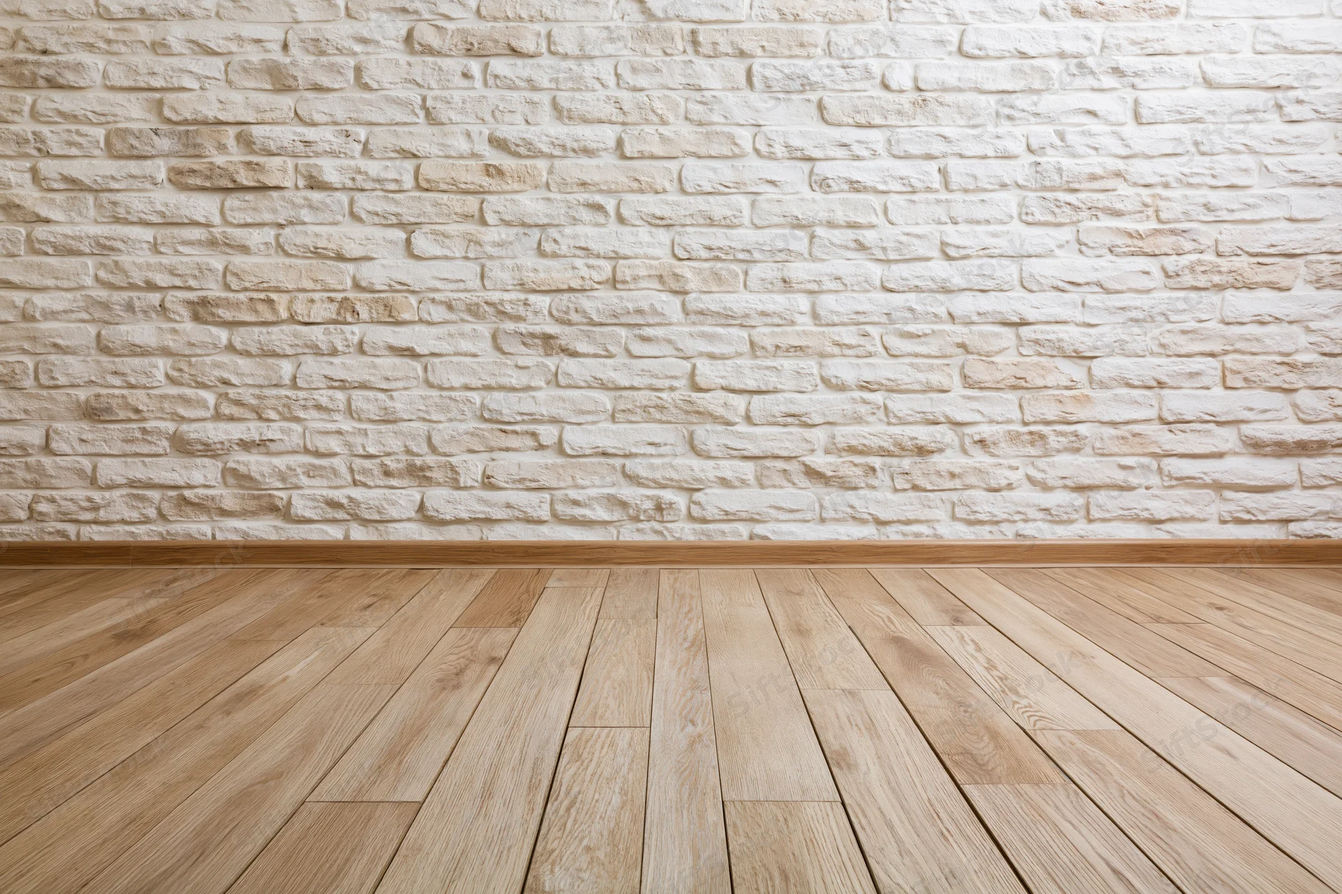 Empty interior room with whitewashed stacked stone brick wall and light wood plank flooring