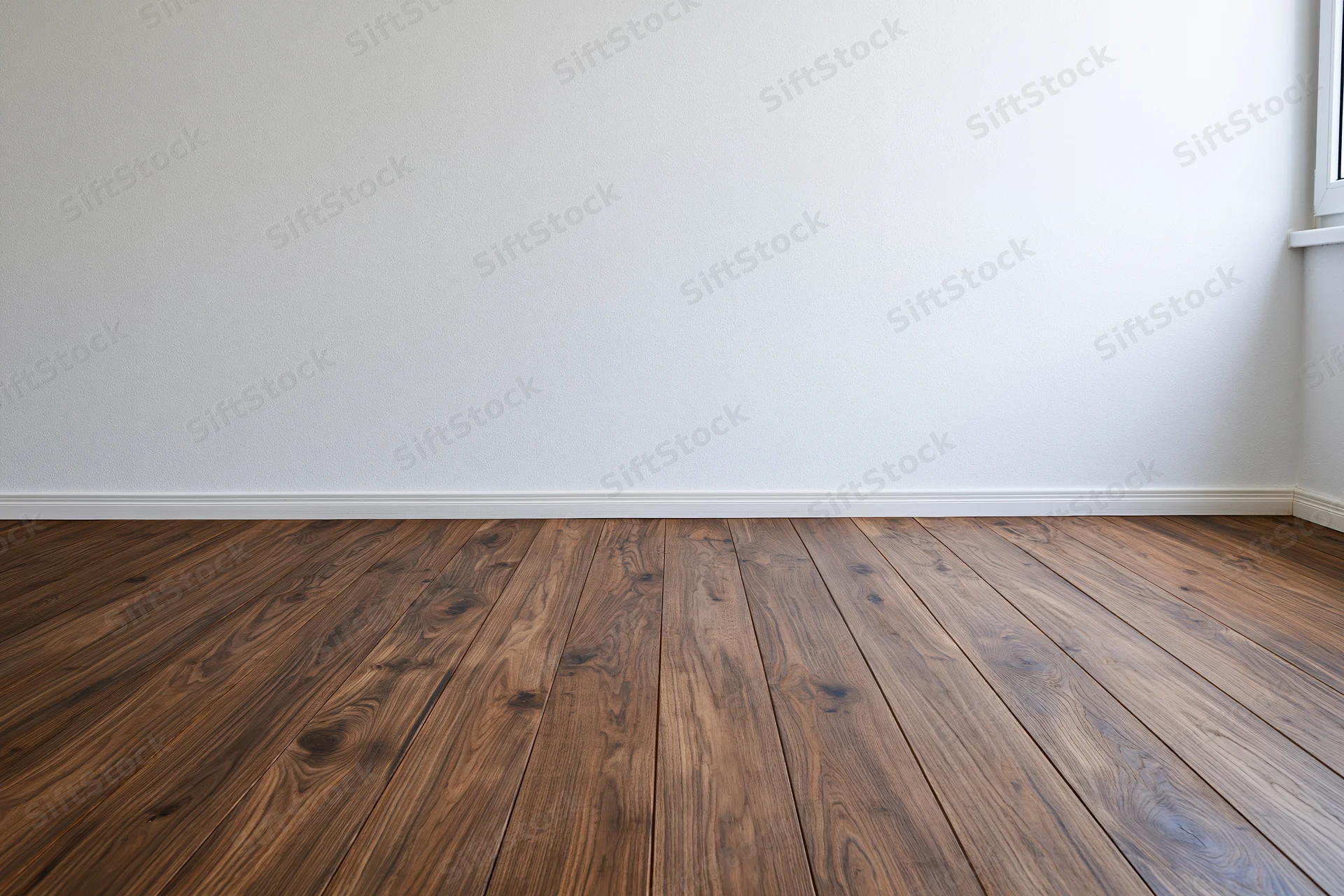 Empty room with white wall and dark wood flooring meeting at baseboard corner near window sill