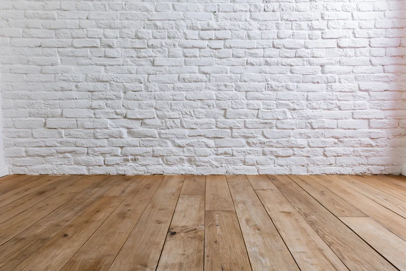 Empty room with white painted brick wall and wooden plank floor