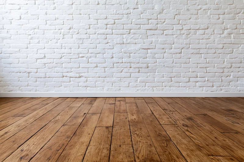 Empty room with white painted brick wall and wooden floor