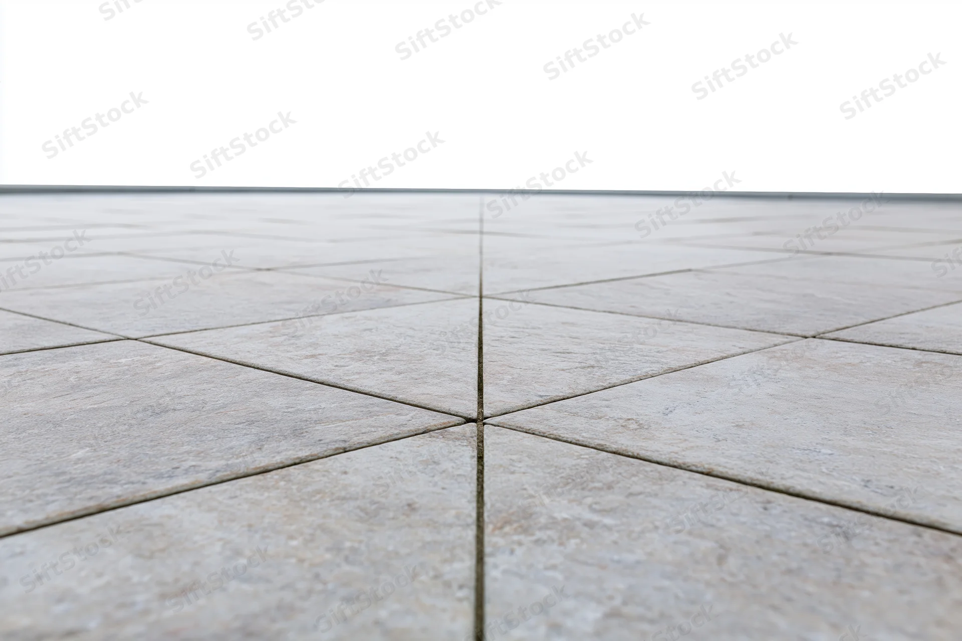 Light grey stone tile floor arranged in square pattern receding into perspective with visible grout lines