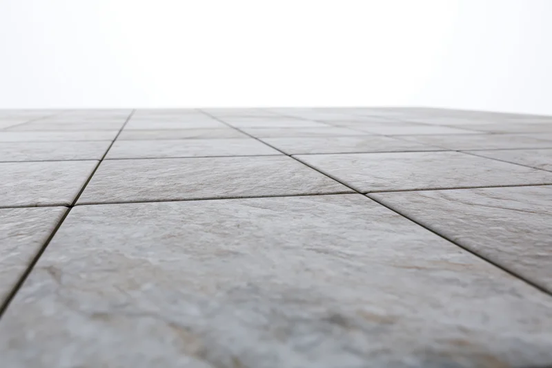 Light grey stone tiles arranged in a receding perspective on a flat outdoor floor