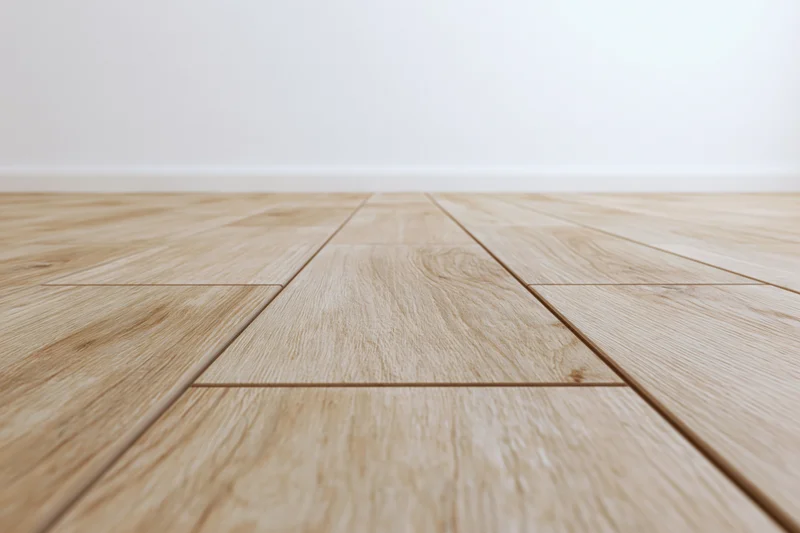 Light oak wood plank floor stretching toward a plain white wall in an empty interior space