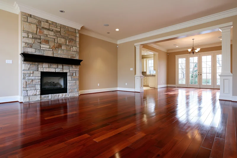 Empty luxury living room with dark cherry hardwood floor and stone fireplace