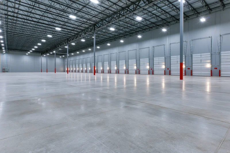 Empty modern warehouse interior with polished concrete floor and metal truss ceiling