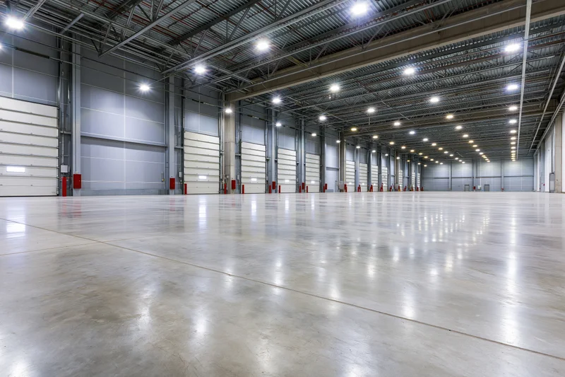 Empty modern warehouse interior with polished concrete floor and metal ceiling structure