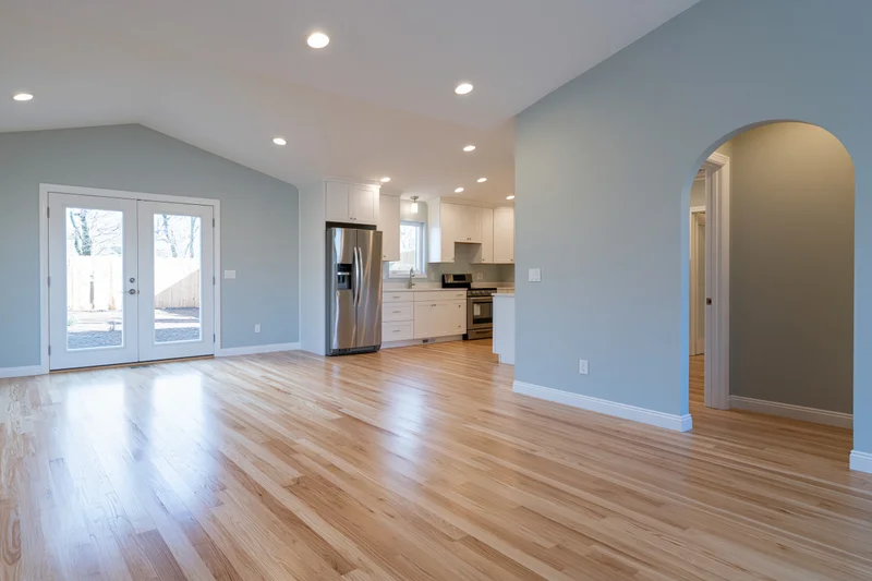 Open-plan kitchen and living area with hardwood flooring and white cabinetry in a residential home