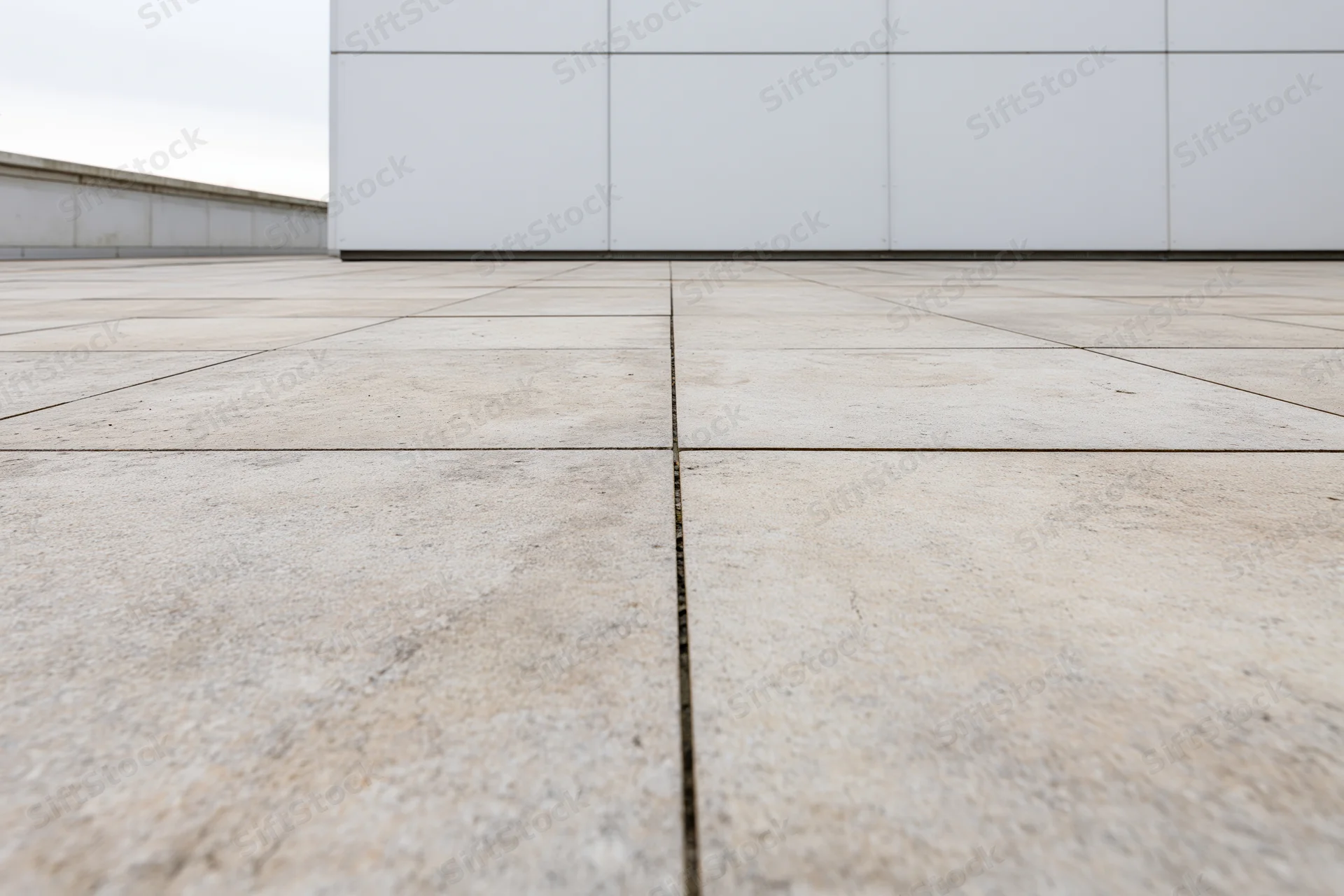 Large beige concrete paving slabs arranged in a grid on an empty outdoor plaza