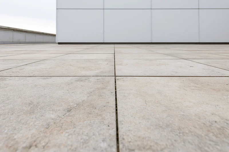 Large beige concrete paving slabs arranged in a grid on an empty outdoor plaza