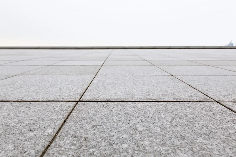 Stone tile plaza floor receding into the distance under overcast sky
