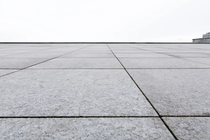 Stone tile plaza floor receding into the distance under overcast sky
