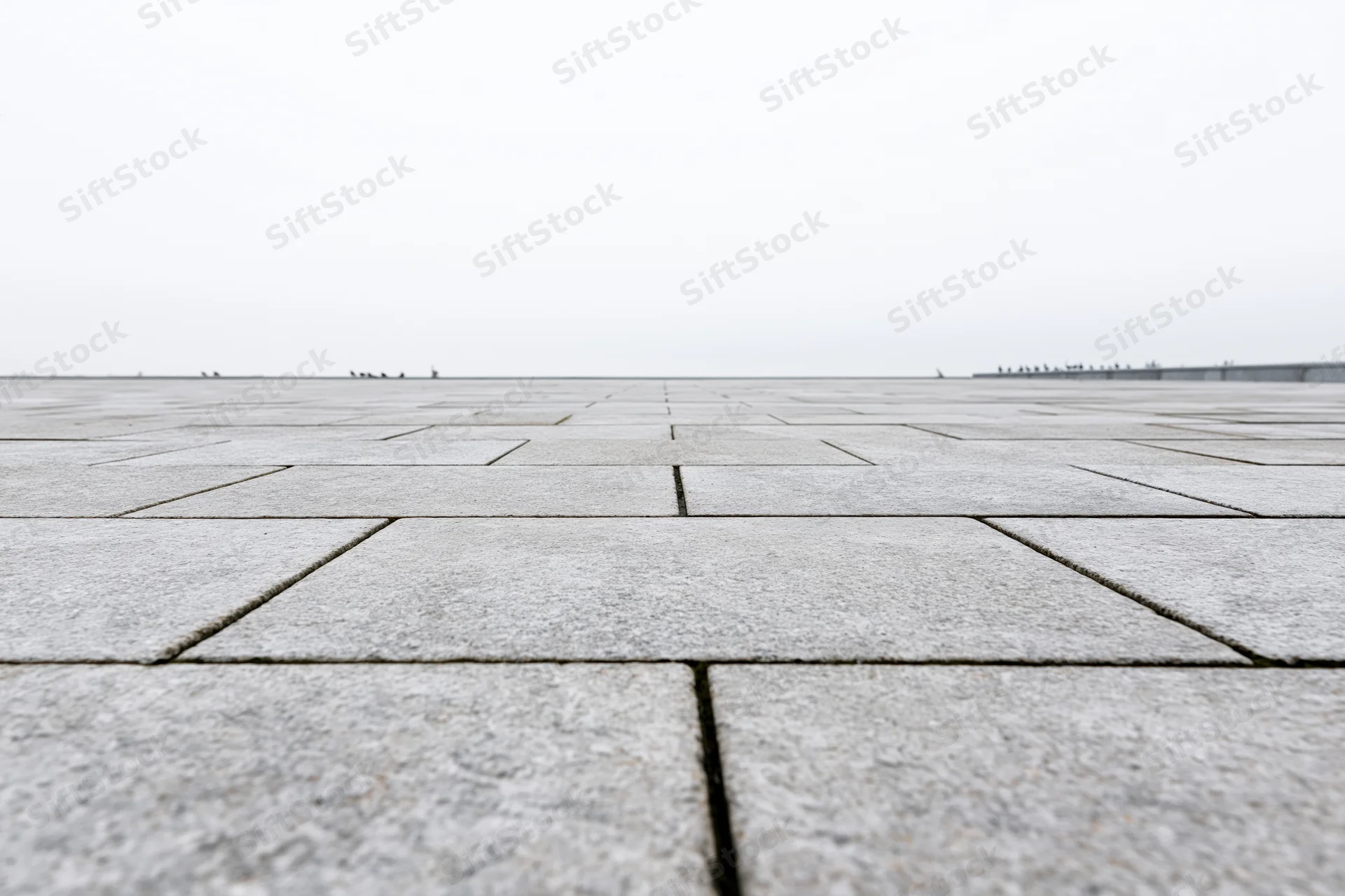Stone tile plaza floor stretching to the horizon under overcast sky