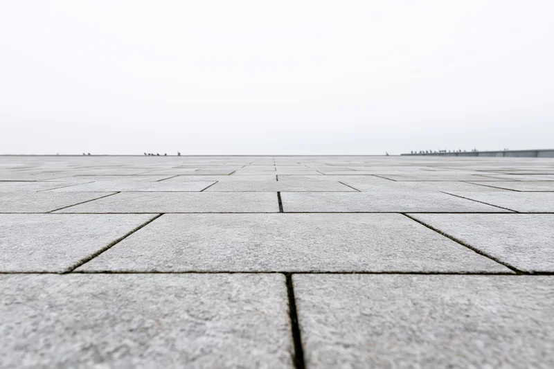 Stone tile plaza floor stretching to the horizon under overcast sky