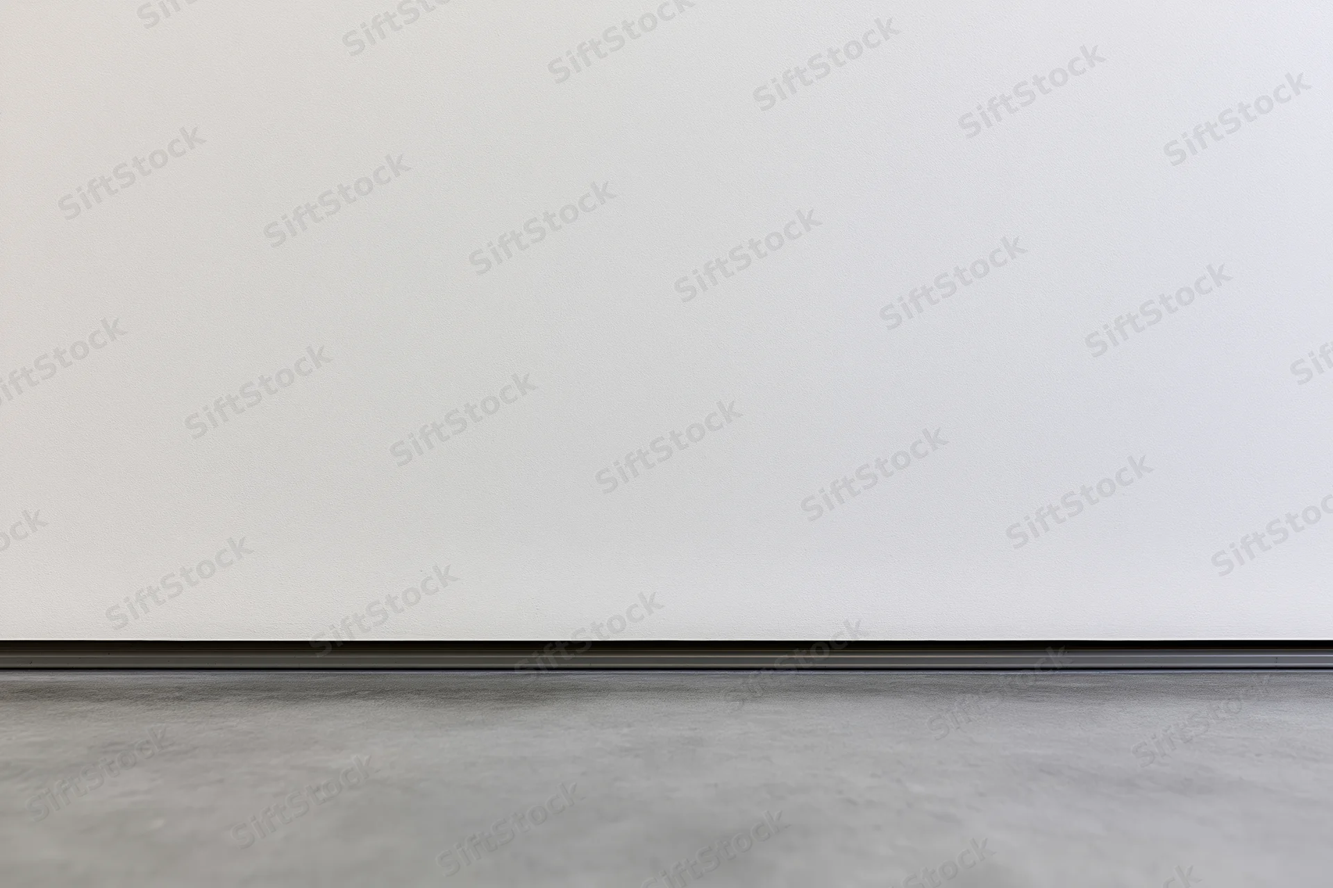 White wall meeting gray concrete floor in empty room interior