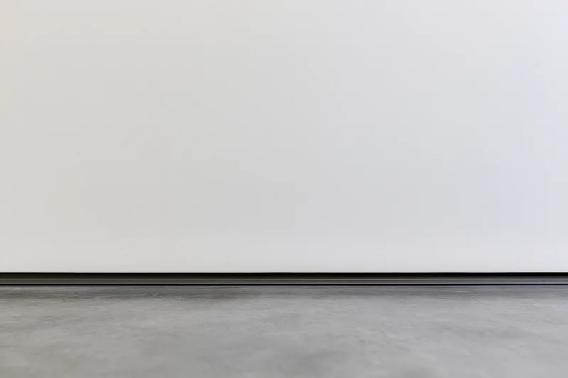 White wall meeting gray concrete floor in empty room interior