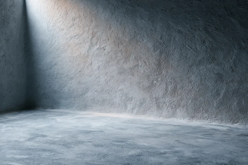 Textured concrete wall and floor in a studio corner with soft lighting and shadow gradient