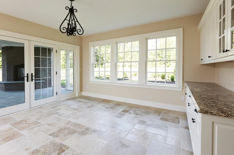 Empty breakfast nook with white cabinetry and travertine tile flooring in a newly constructed home interior