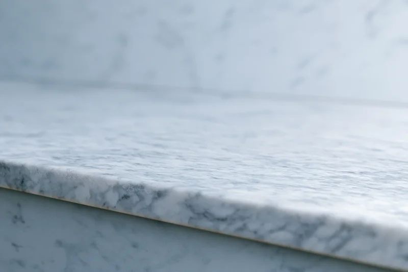 White marble countertop meeting a marble wall in a kitchen interior