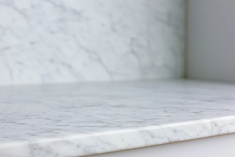 White marble countertop meeting a marble wall in a kitchen interior