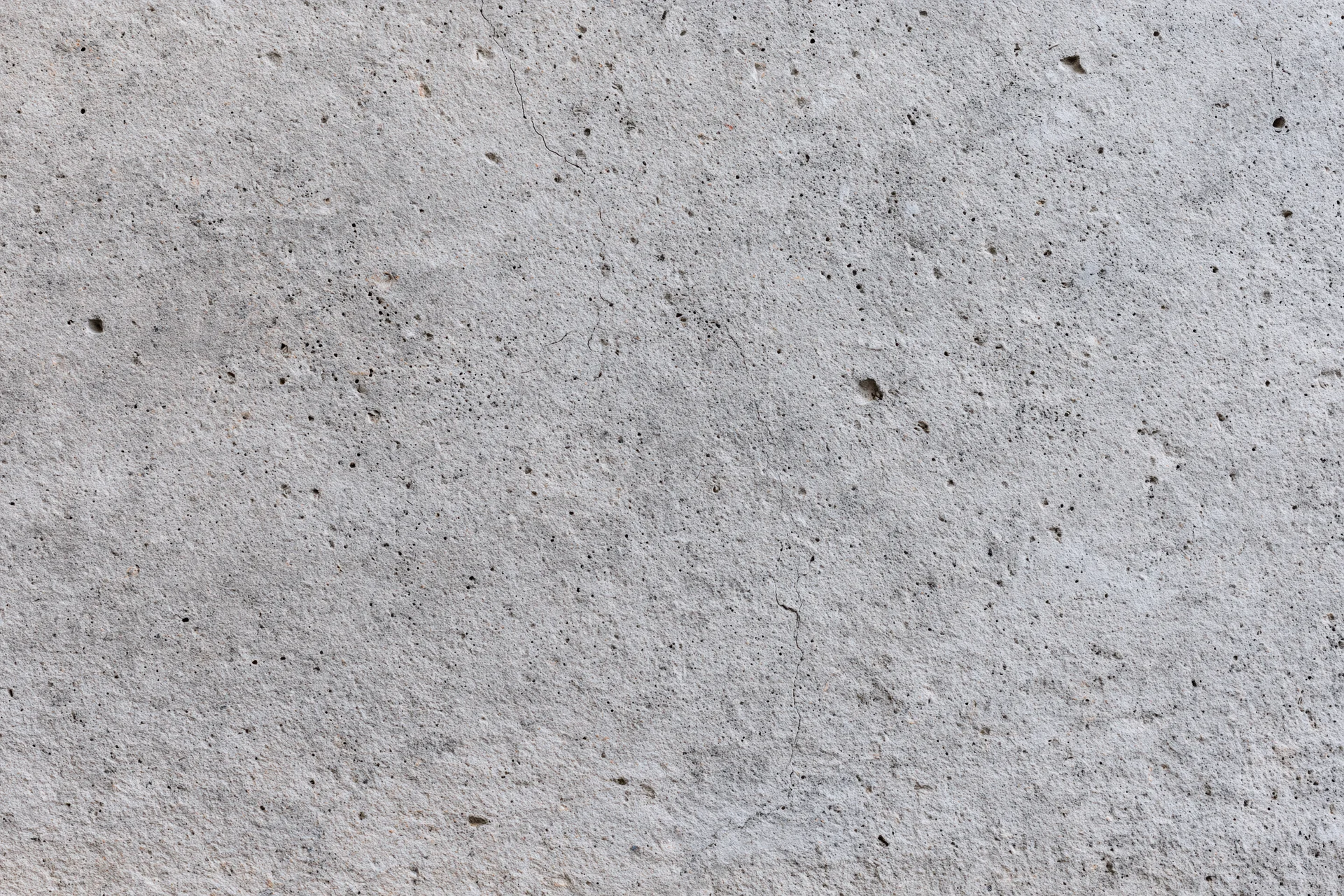 Flat concrete wall surface filling the frame with visible texture and small imperfections