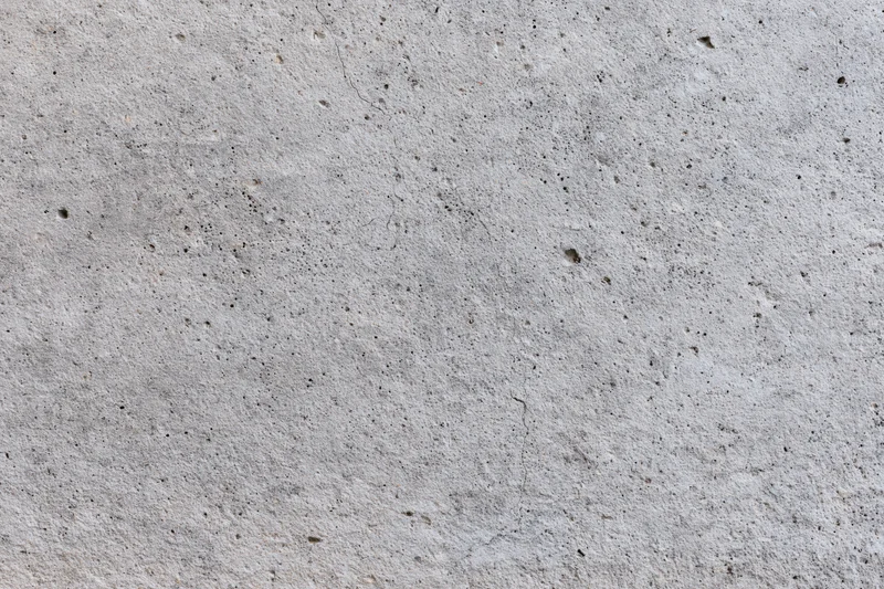 Flat concrete wall surface filling the frame with visible texture and small imperfections
