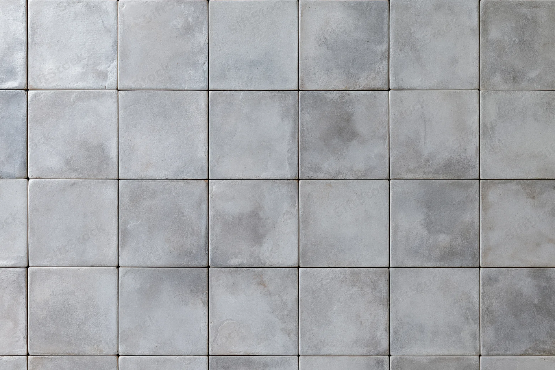 Concrete tile floor surface arranged in uniform grid pattern with gray grout lines