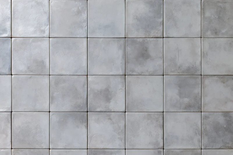 Concrete tile floor surface arranged in uniform grid pattern with gray grout lines