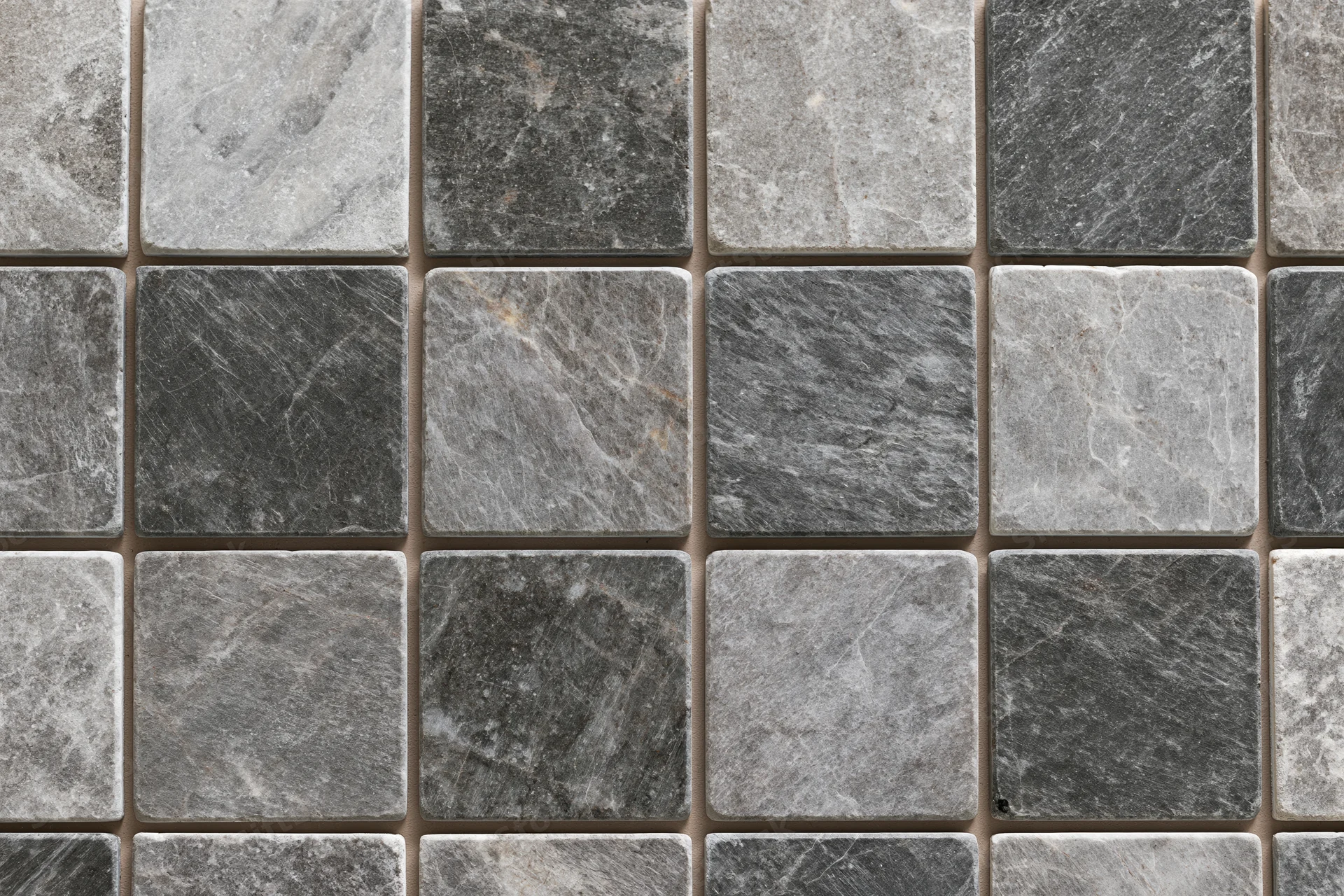 Grid of square stone tiles arranged in a mosaic pattern on a flat surface