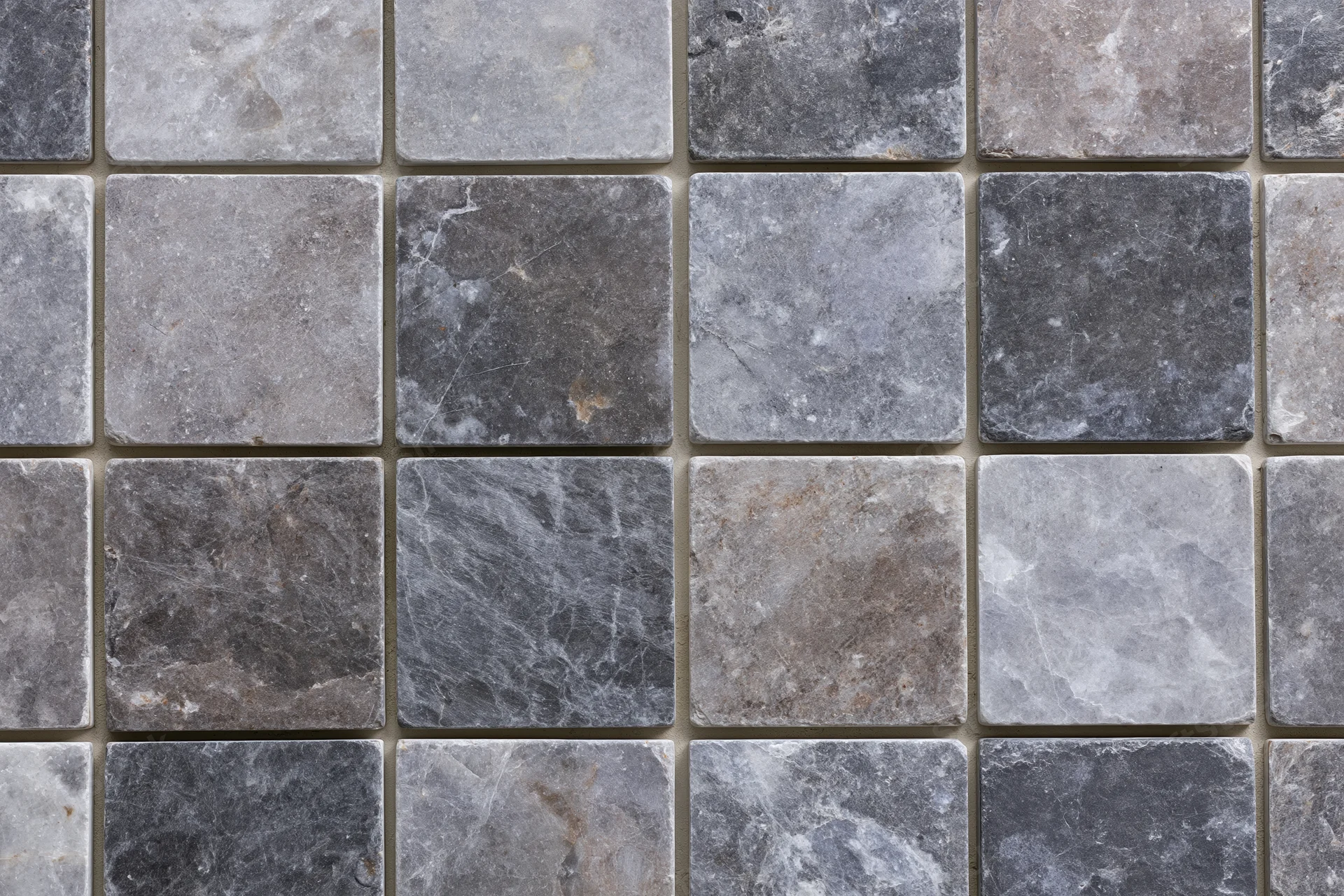 Grid of square stone tiles arranged in a mosaic pattern covering a flat surface