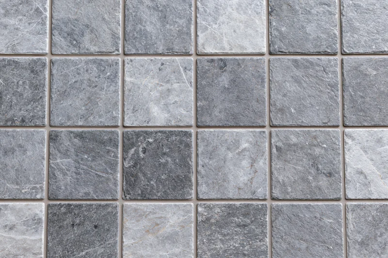 Grid of square stone tiles arranged in a pattern covering a surface