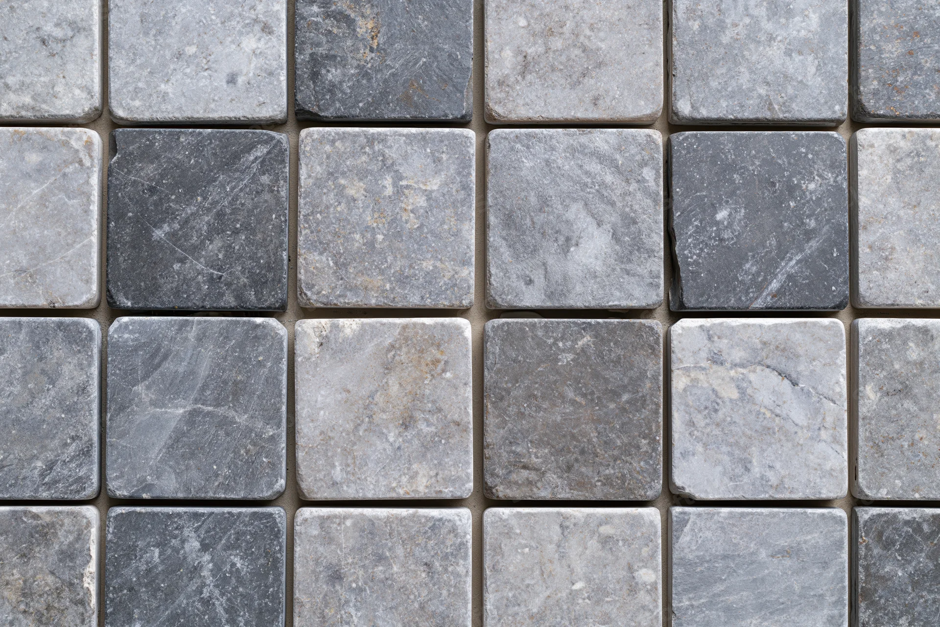 Grid of square stone tiles arranged in a pattern covering a surface