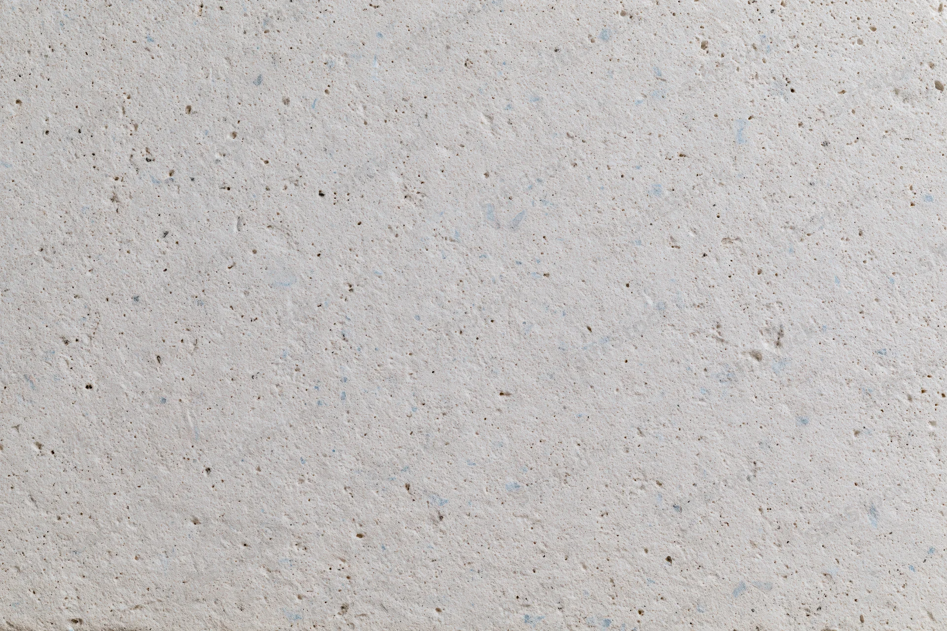 Close-up of a smooth concrete or limestone surface with natural speckles and pores