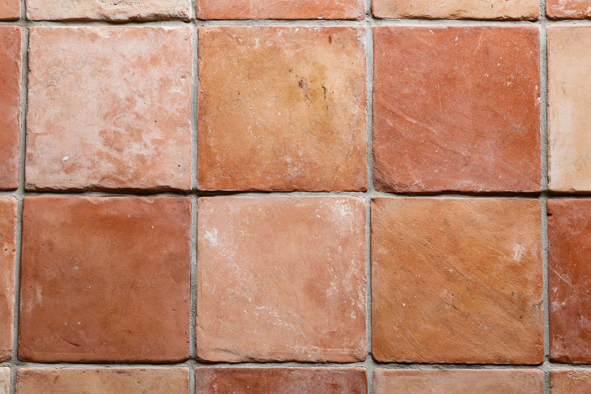 Aged terracotta floor tiles arranged in a grid pattern with visible grout lines