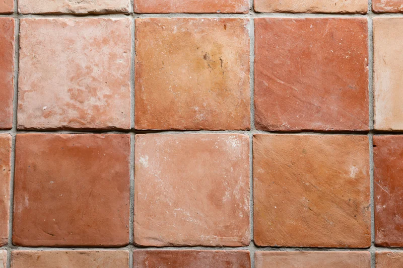 Aged terracotta floor tiles arranged in a grid pattern with visible grout lines