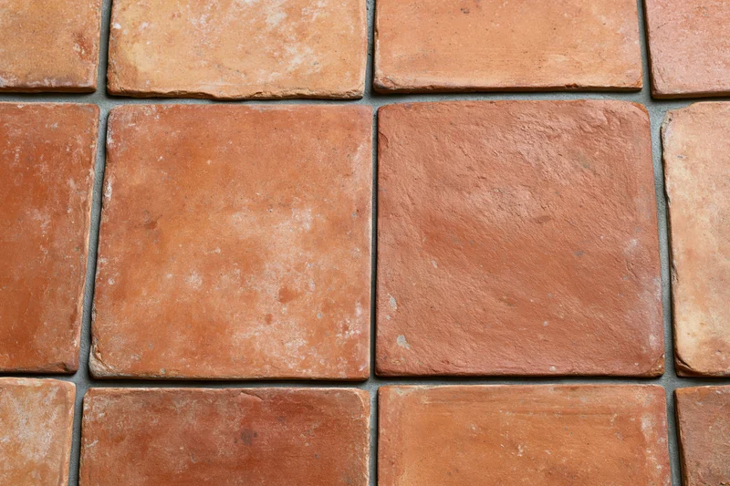 Aged terracotta floor tiles arranged in a grid pattern with visible grout lines
