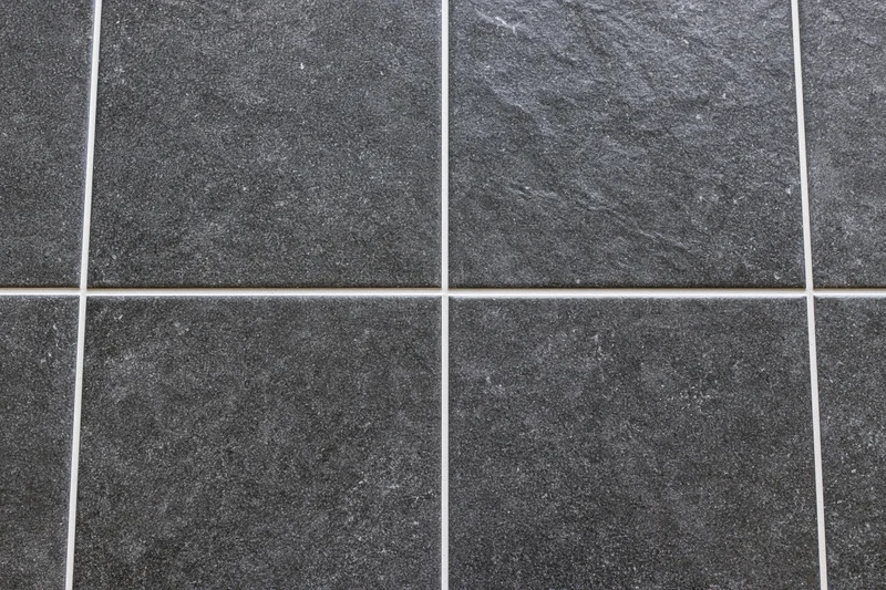Dark charcoal ceramic floor tiles arranged in a grid pattern with white grout lines
