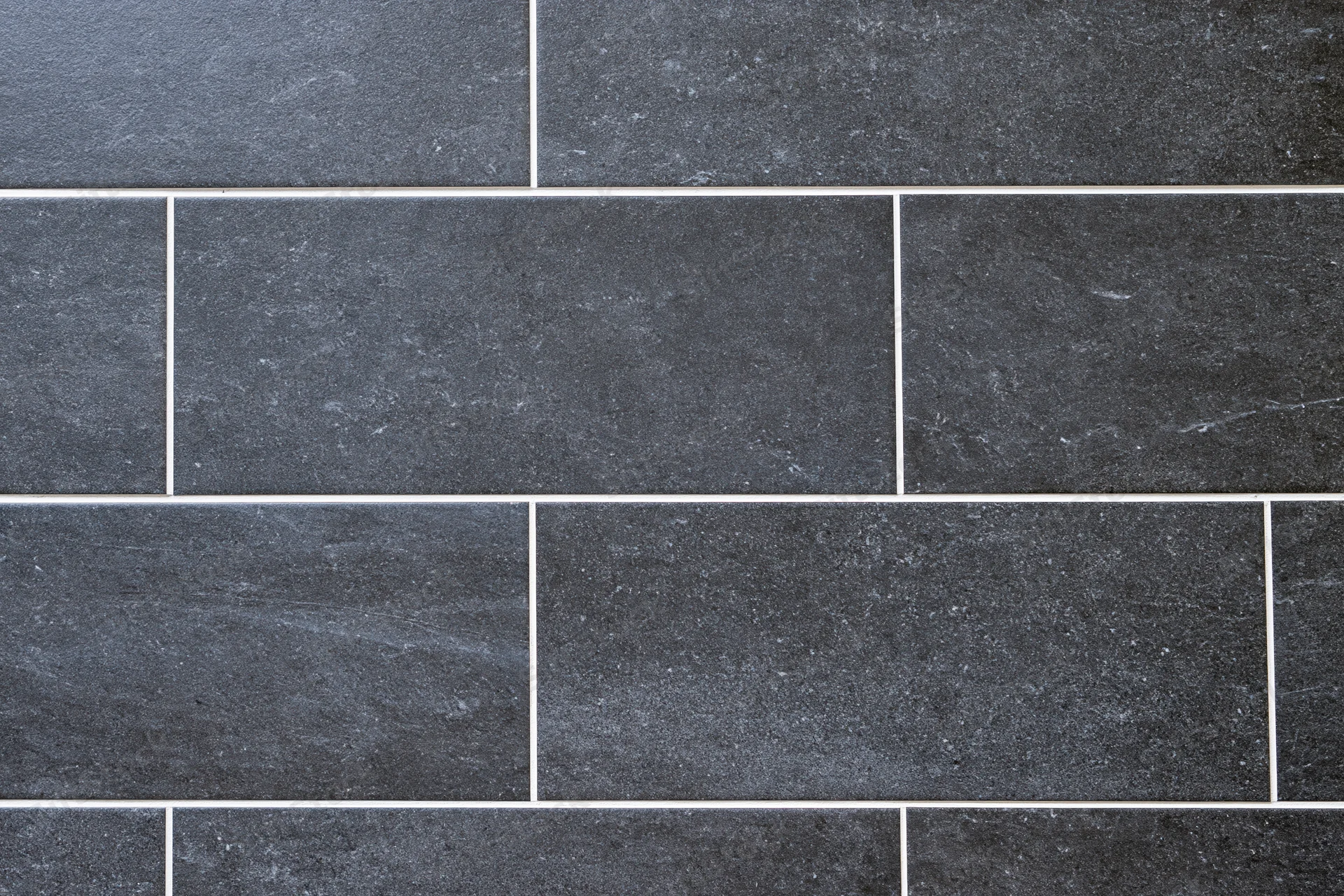 Dark charcoal ceramic floor tiles arranged in a brick pattern with white grout, close-up view