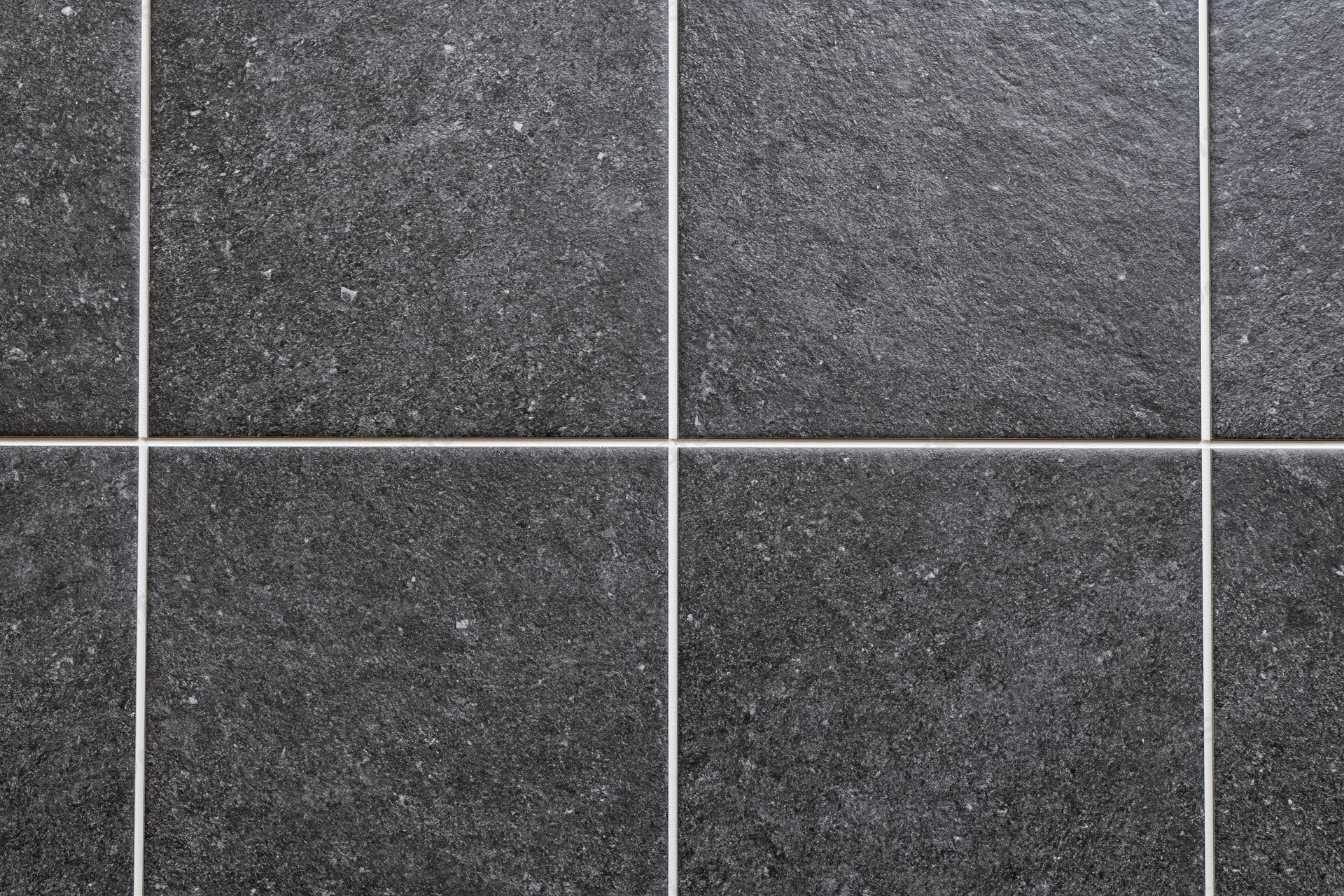 Dark charcoal ceramic floor tiles arranged in a grid pattern with white grout lines