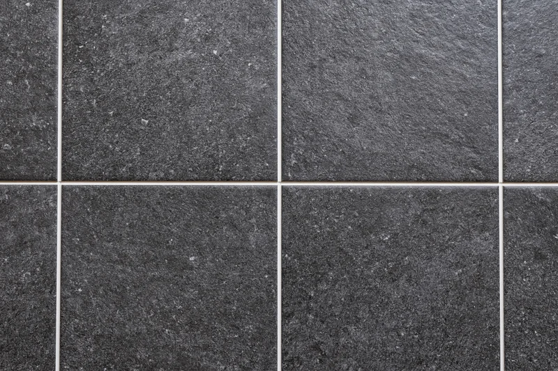 Dark charcoal ceramic floor tiles arranged in a grid pattern with white grout lines