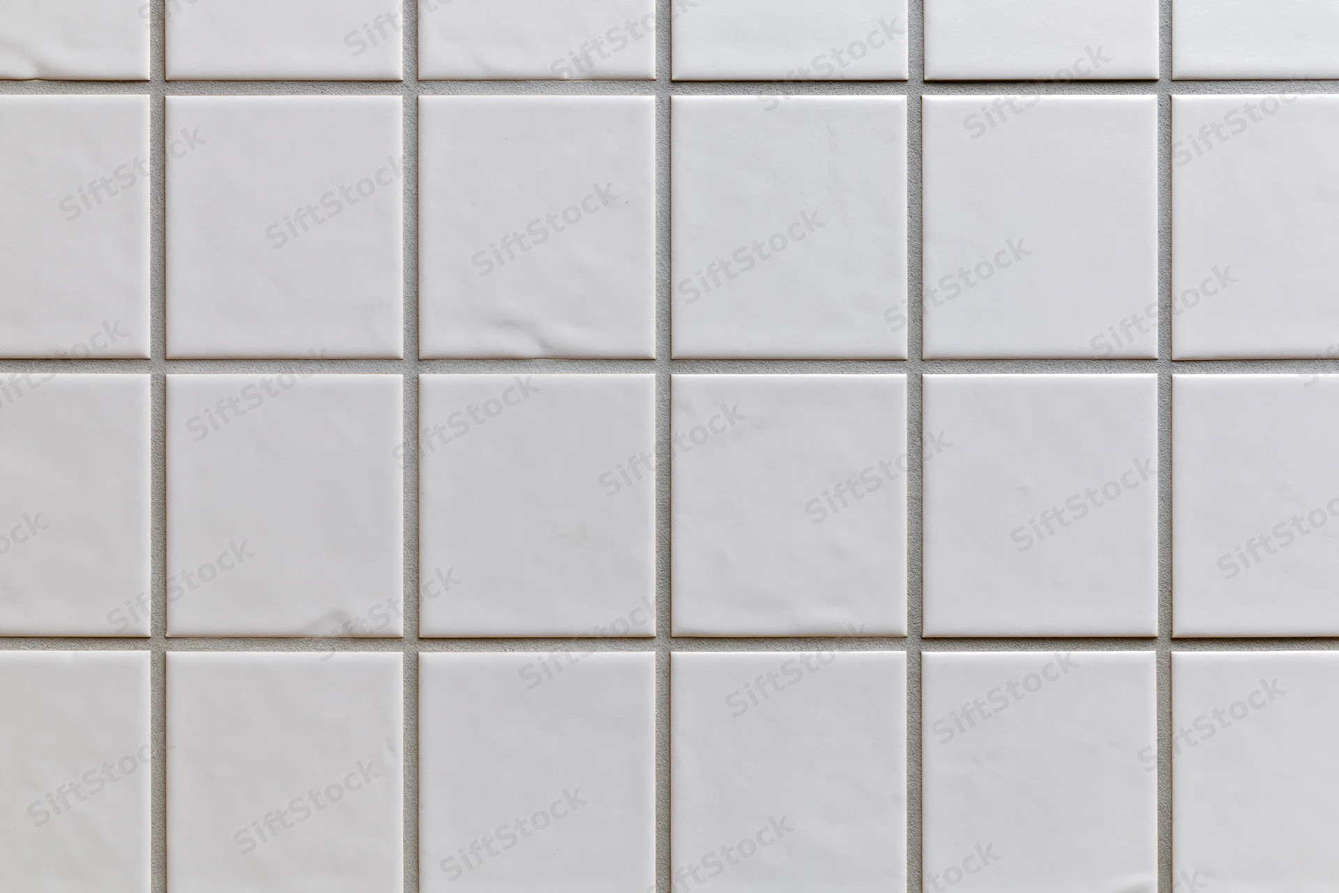 White ceramic tiles arranged in a grid pattern covering a wall surface
