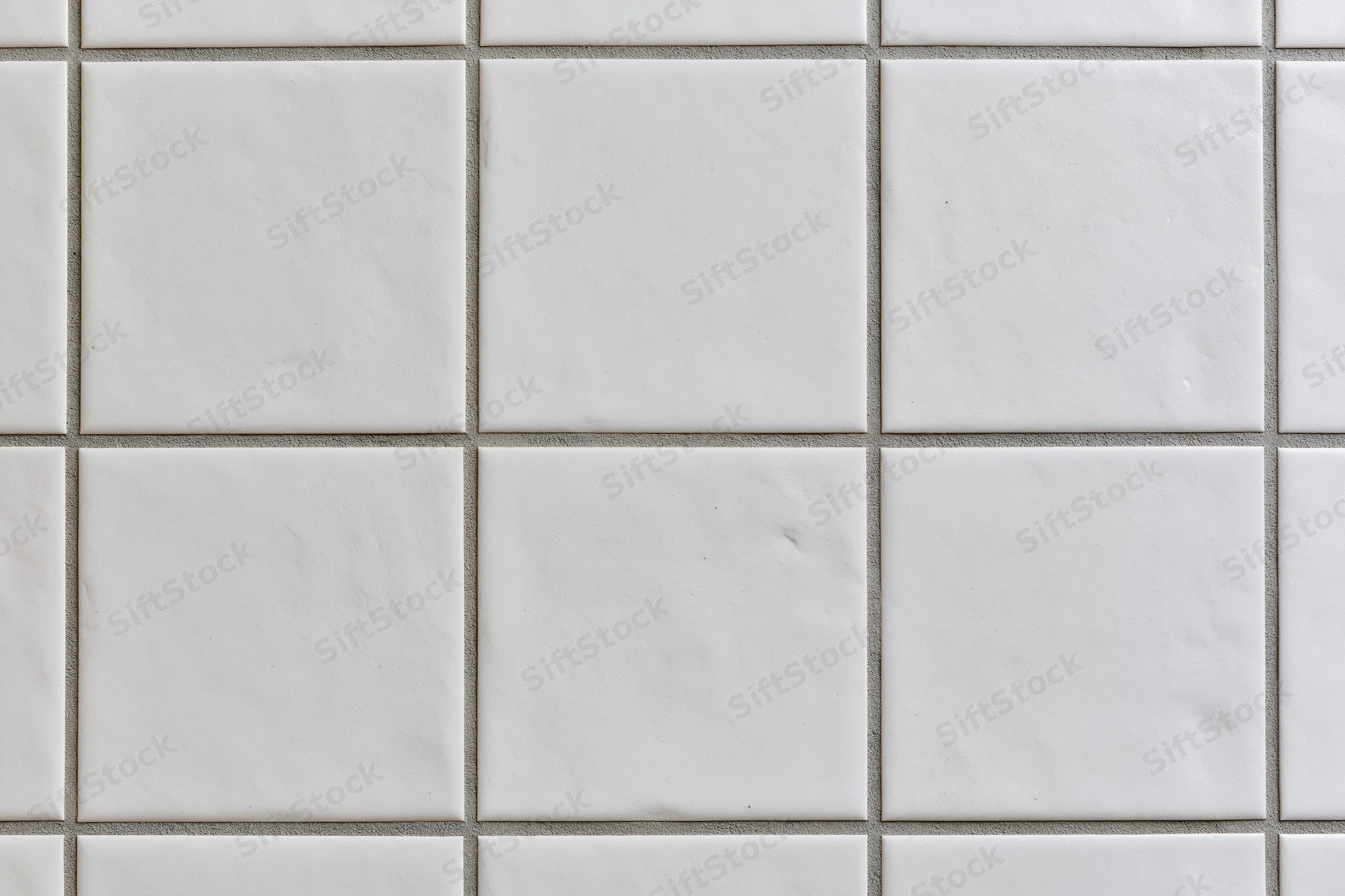 White ceramic tiles arranged in a grid pattern on a wall surface